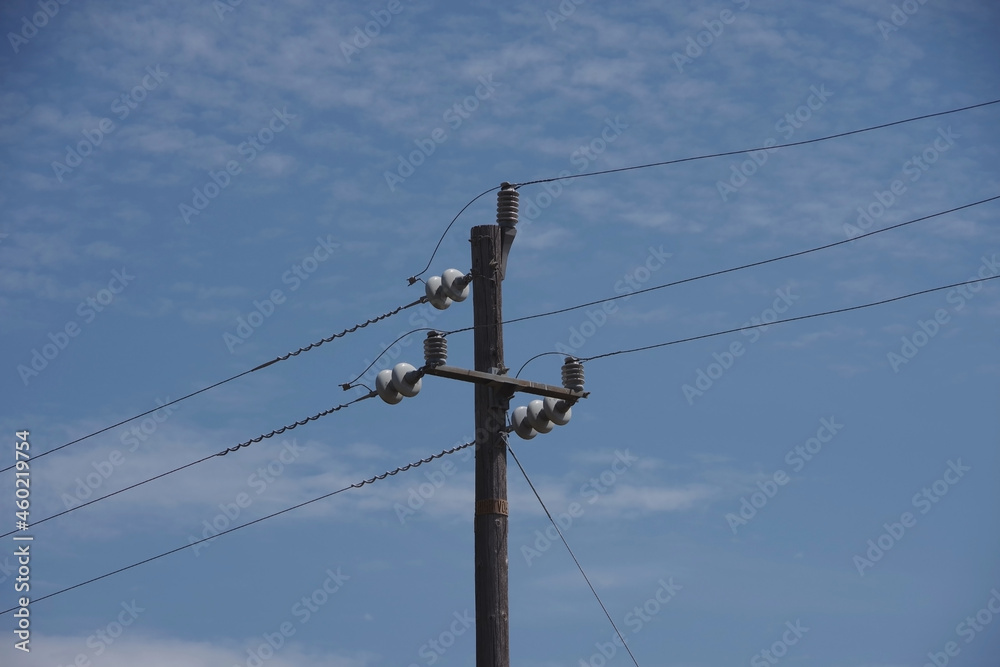 Simple rural electricity distribution pylon and power lines under blue sky Simple rural electricity distribution pylon and power lines under blue sky