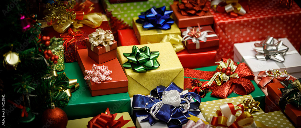 Close up shot of a lot of Merry Christmas eve wrapped present gift boxes stack with colorful ribbons and bows with decoration Xmas pine tree with glossy sphere balls bells socks ice flakes nearby Close up shot of a lot of Merry Christmas eve wrapped present gift boxes stack with colorful ribbons and bows with decoration Xmas pine tree with glossy sphere balls bells socks ice flakes nearby