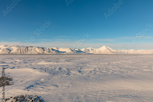 Arctic winter landscape with frozen fjord and snow covered mountains on Svalbard, Norway