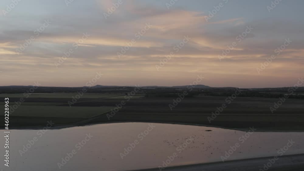 Aerial shot of a dam in San Miguel, Mexico, with light yellow sunset clouds and many birds resting on the water Aerial shot of a dam in San Miguel, Mexico, with light yellow sunset clouds and many birds resting on the water