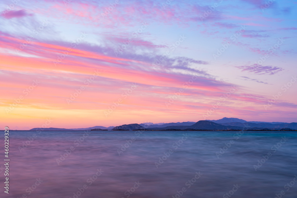 Stunning seascape with a romantic and relaxing sunrise reflected on a calm water flowing in the foreground. Golfo Aranci, Sardinia, Italy. Stunning seascape with a romantic and relaxing sunrise reflected on a calm water flowing in the foreground. Golfo Aranci, Sardinia, Italy.