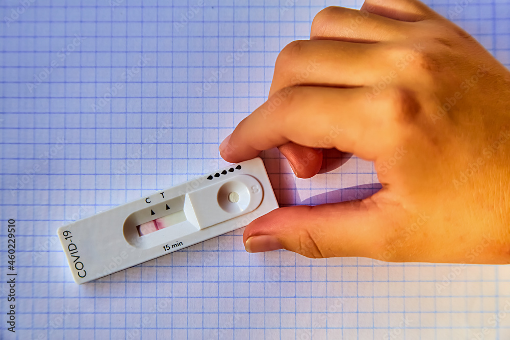children's hand holds the Fast and simple Self-Test the COVID-19 Antigen.he provides results in 15 minutes at home. using a nasal swab. on checkered school leaflet children's hand holds the Fast and simple Self-Test the COVID-19 Antigen.he provides results in 15 minutes at home. using a nasal swab. on checkered school leaflet