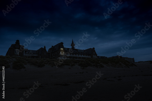 old spooky clinic in the dunes of berck at night. two windows are mysteriously illuminated. photo