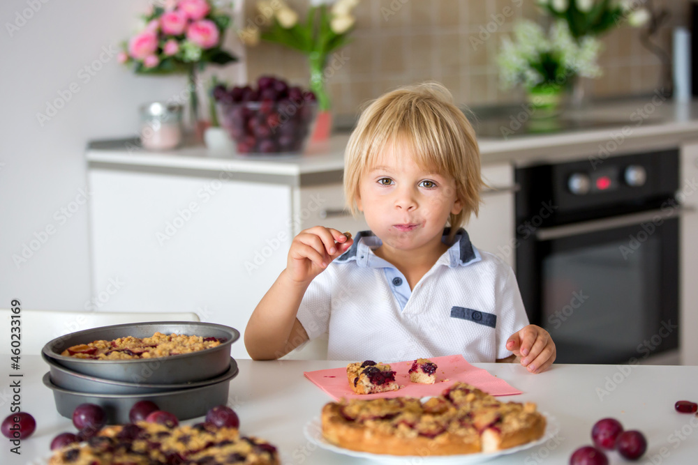 Cute little toddler child, eating homemade plum pie at home