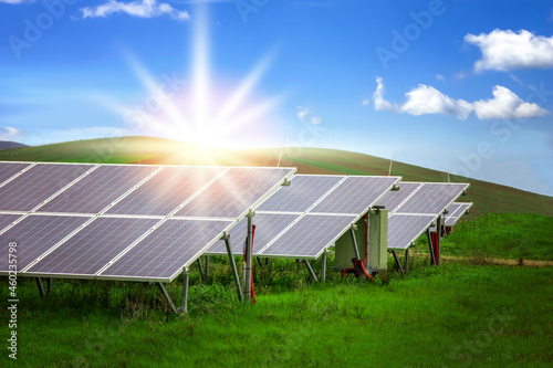 Energy storage system. Photovoltaics solar panels in power station  alternative energy from the sun in field with green grass and mountains at the horizon