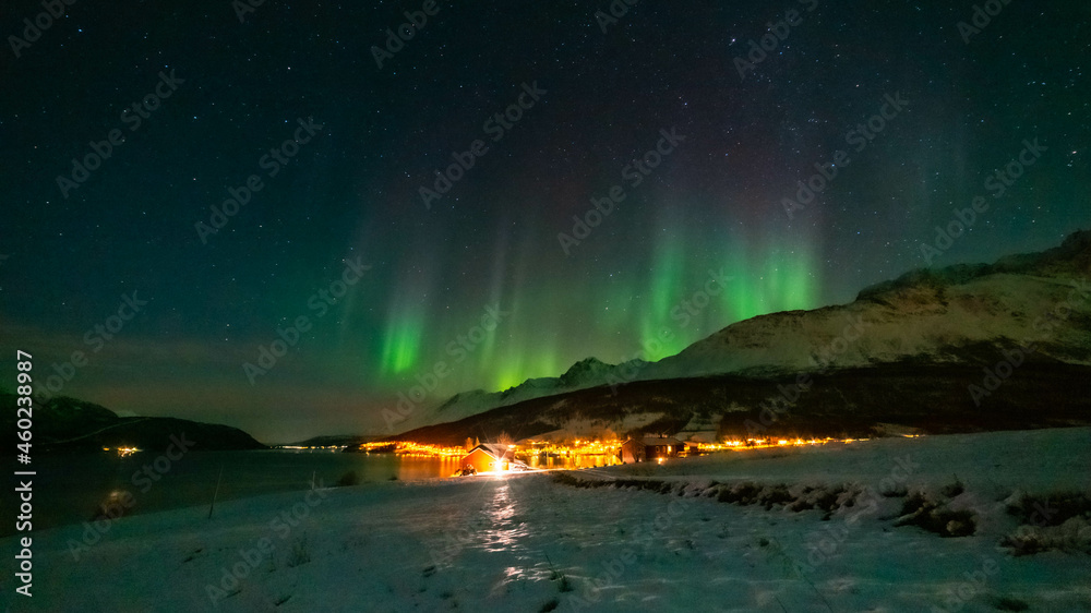 Nordlichter wie eine Krone über Lakselvbukt in den Lyngenalps, Norwegen. Aurora Borealis over snowy mountains. village on illuminated night