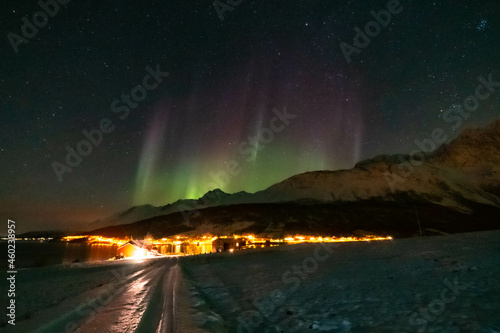 Nordlichter wie eine Krone über Lakselvbukt in den Lyngenalps, Norwegen. Aurora Borealis over snowy mountains. village on illuminated night © Dieter