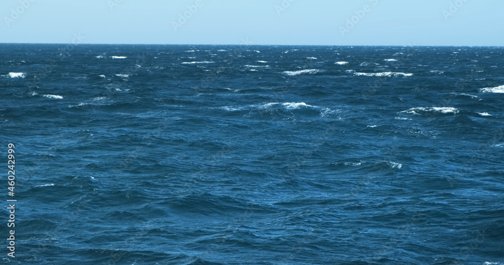 Azure sea with waves on sunny windy day. White cruise yacht sailing blue Red sea surface, view of moving boat. Yachting tour in Egypt blue sky above horizon. Natural marine background. Nautical voyage