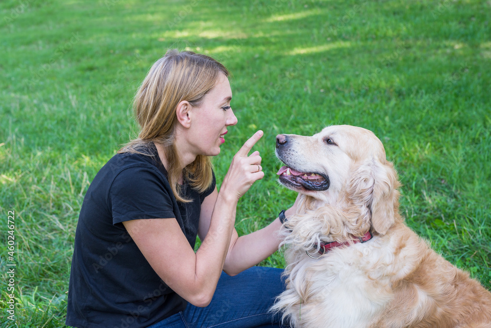 Young woman playing with her dog retriever touching the dog's nose while lying on the grass in the park. Young woman playing with her dog retriever touching the dog's nose while lying on the grass in the park.