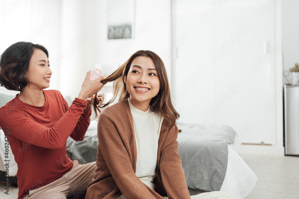 Young beautiful Asian couple love friend woman do hair on bed in bedroom.