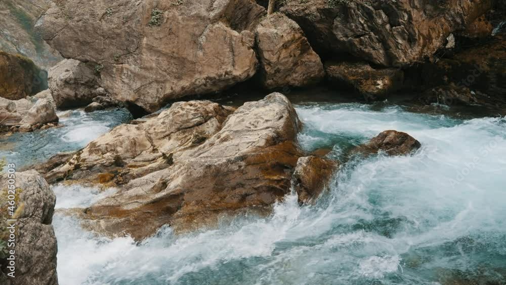 Rapid flow of water in a mountain river with rapids and big stones Rapid flow of water in a mountain river with rapids and big stones