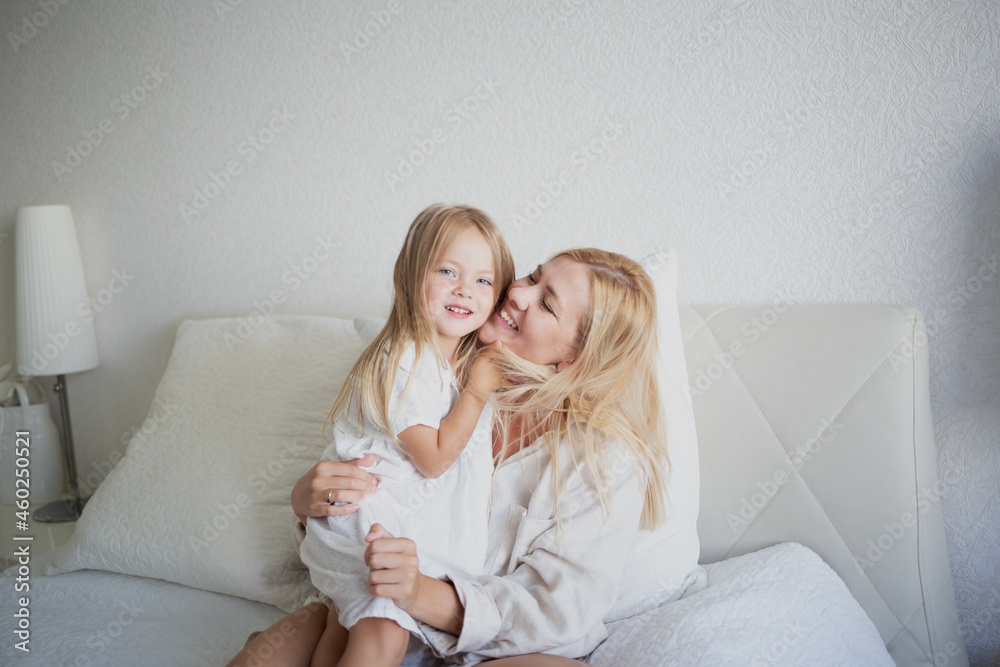 little girl hugging with mom while sitting on the bed in the bedroom