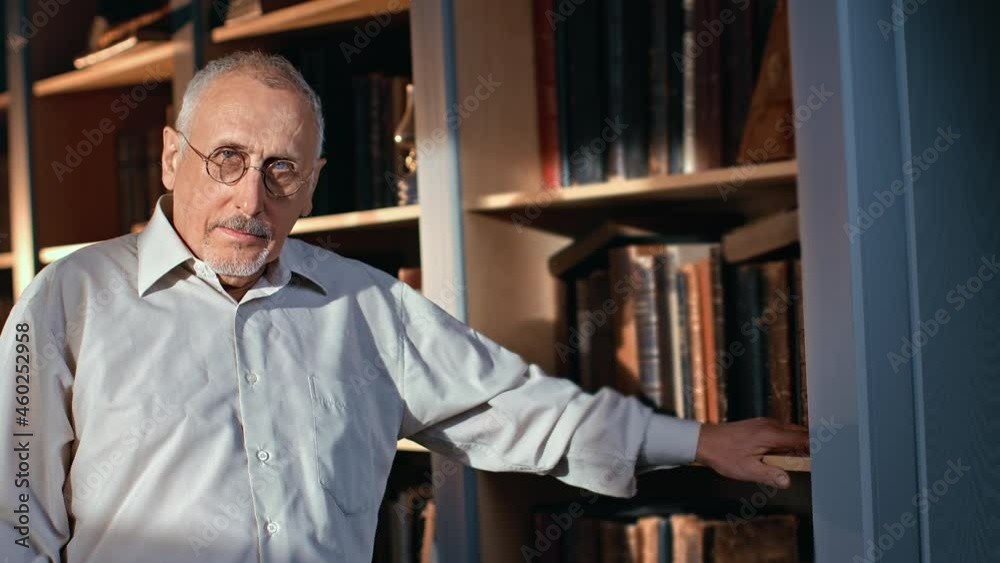 Portrait smiling 70s elderly man scientist writer author researcher posing at library Portrait smiling 70s elderly man scientist writer author researcher posing at library