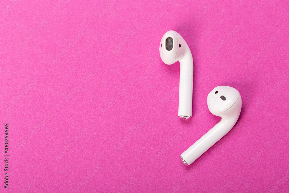 Modern wireless bluetooth headphones with charging case on pink background. The concept of modern technology. Modern wireless bluetooth headphones with charging case on pink background. The concept of modern technology.