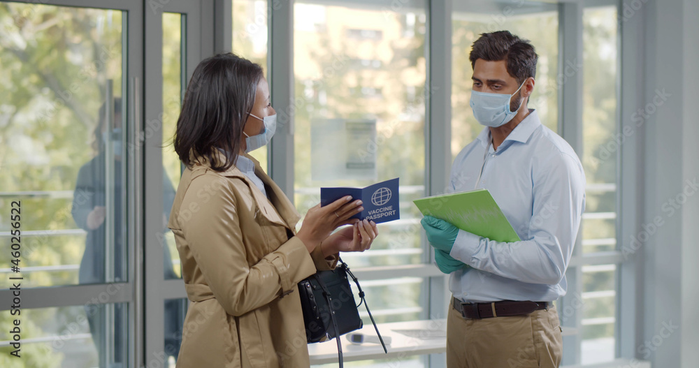 Fototapeta premium People in mask enter building and show vaccination passport to security