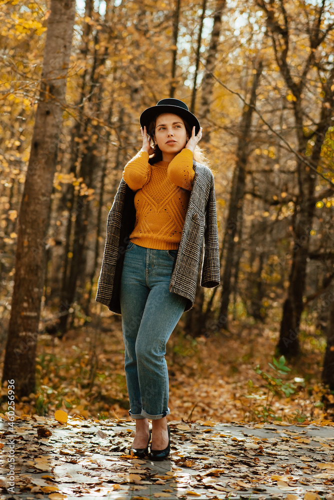 a young girl in a coat and hat walks through the autumn Park a young girl in a coat and hat walks through the autumn Park