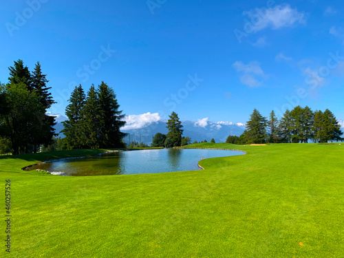 Fotografia Crans Sur Sierre Golf Course with Water Pond on Fairway with Mountain View in Crans Montana in Valais, Switzerland