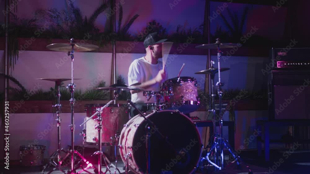 A professional male artist plays a drum kit. Night show in a musical instrument recording studio. The drummer knocks and beats, Repetition of rock or metal music band. Music party with colored lights A professional male artist plays a drum kit. Night show in a musical instrument recording studio. The drummer knocks and beats, Repetition of rock or metal music band. Music party with colored lights
