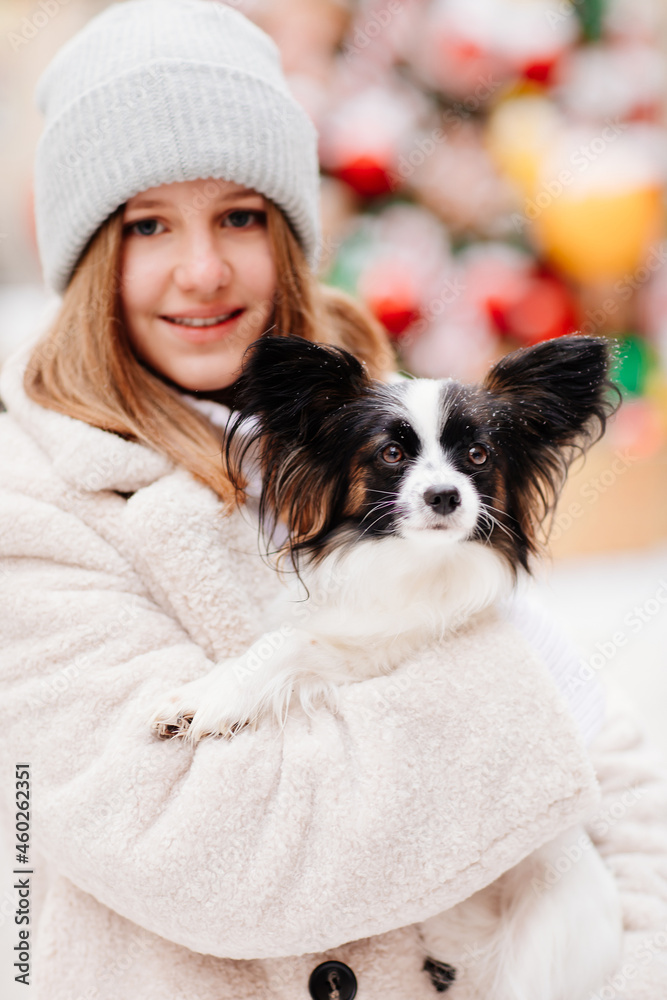 a beautiful and happy girl warms a small dog papillon in her coat. a beautiful and happy girl warms a small dog papillon in her coat.