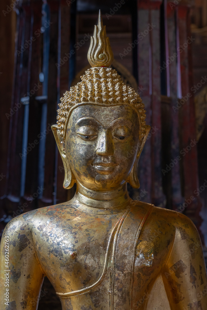 Beautiful ancient gilded Buddha statue with gold leaf inside heritage landmark Wat Phan Tao buddhist temple facade and gate, Chiang Mai, Thailand	
