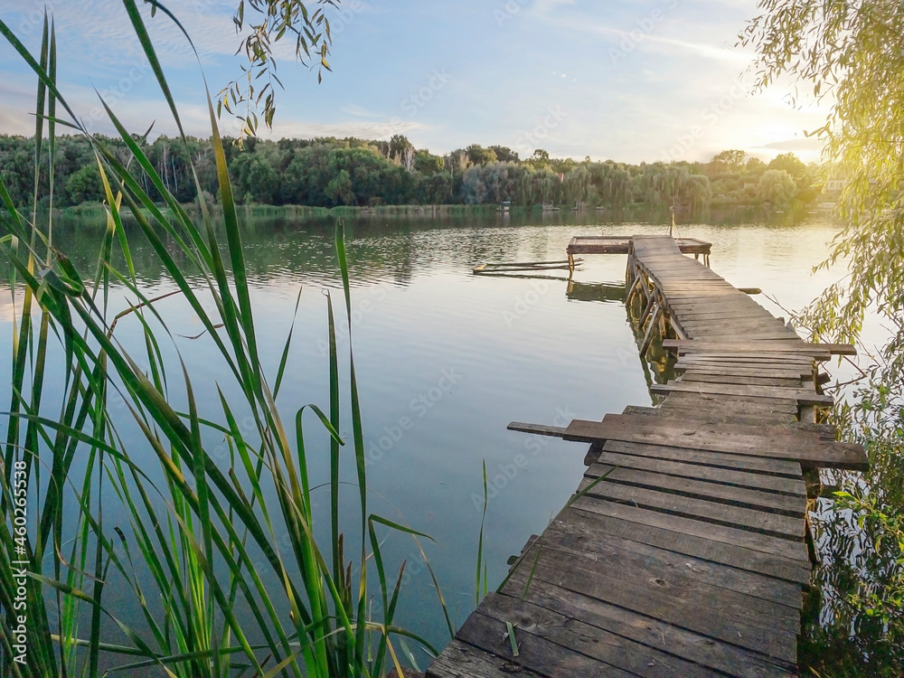 Fishing wooden pier on lake at sunset