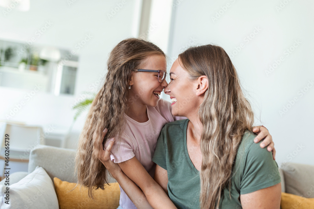 Close up of sweet pretty daughter cuddling with her young mother. Lovely mother embracing her cute daughter on the sofa at home. Close up of sweet pretty daughter cuddling with her young mother. Lovely mother embracing her cute daughter on the sofa at home.