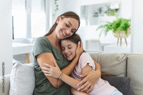 Portrait of happy young mother play hug and cuddle show love cute small preschooler daughter relaxing in living room, smiling mom and little girl child rest enjoy family weekend at home together © Graphicroyalty
