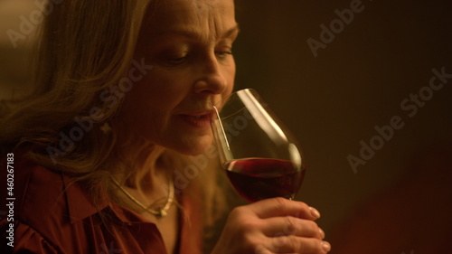 Old woman drinking red wine glass at restaurant date. Upset retirement life