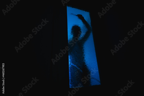 A blurred silhouette in the dark behind the glass.