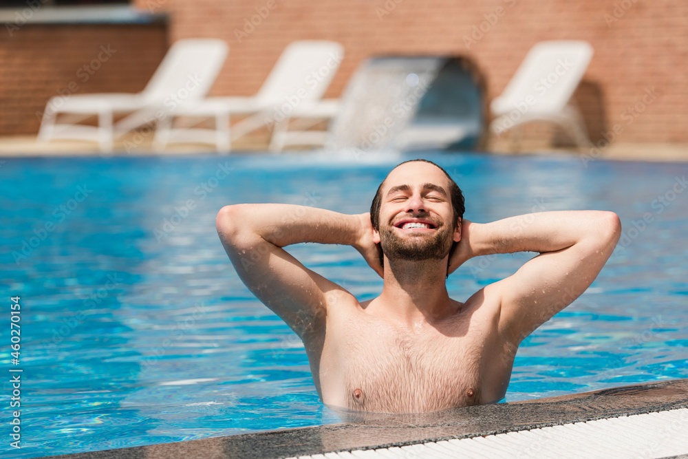 Joyful man relaxing in swimming pool outdoors