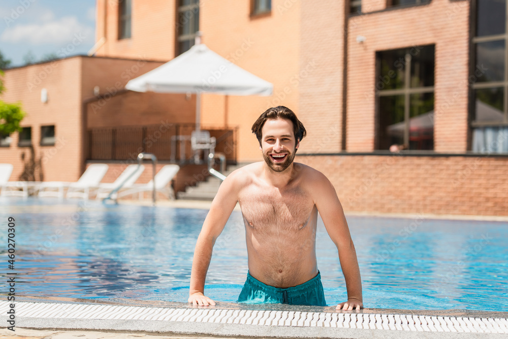 Cheerful man looking at camera near poolside outdoors