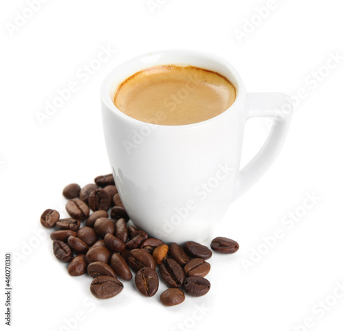 Cup of tasty espresso and scattered coffee beans on white background