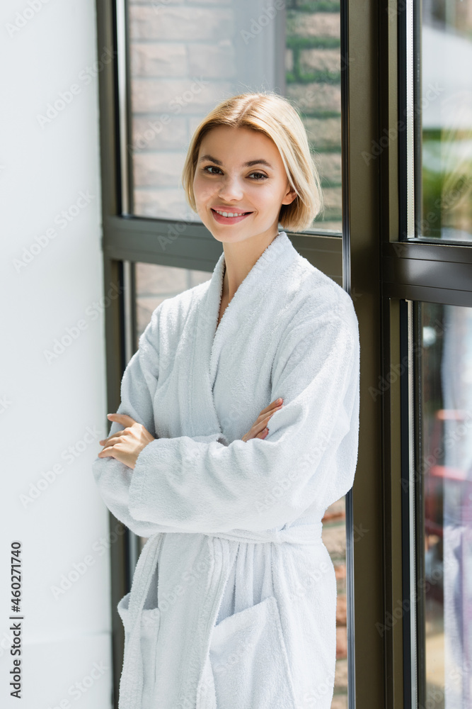 Smiling woman in bathrobe standing with crossed arms near window in spa center Smiling woman in bathrobe standing with crossed arms near window in spa center