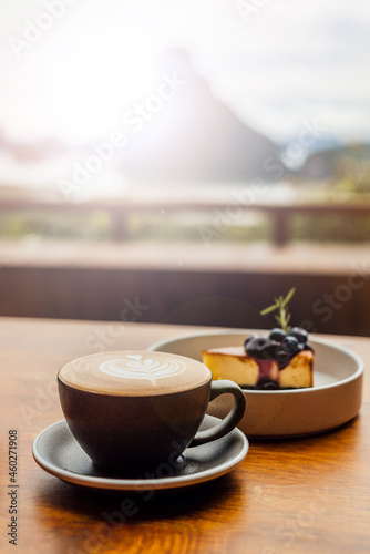 Fototapeta Naklejka Na Ścianę i Meble -  Cheesecake with chocolate and coffee latte art with luxury mountain view in background from Phang Nga bay in Thailand