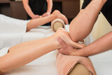 Cropped view of masseur doing feet massage to woman on roller in spa center