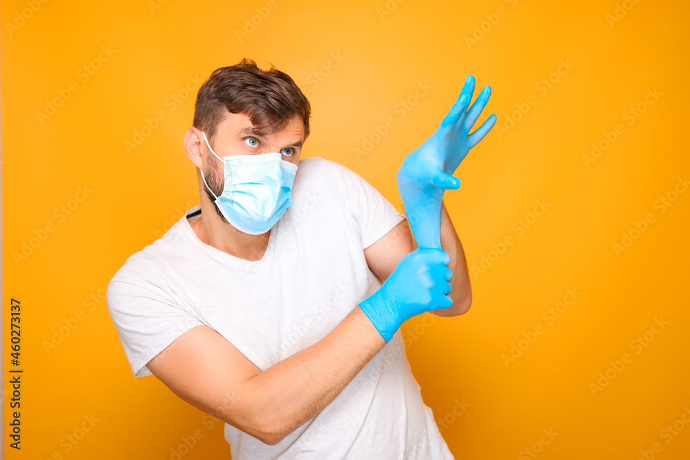 a man in a medical mask puts on sterile blue gloves on his hand. a man in a medical mask puts on sterile blue gloves on his hand.