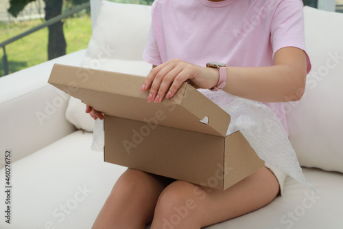 Young woman opening parcel at home, closeup. Internet shopping