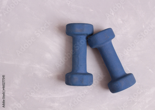 Blue dumbbells for home fitness supply. Objects on a stone background