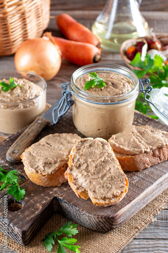 Fresh homemade chicken liver pate on bread on rustic background photo