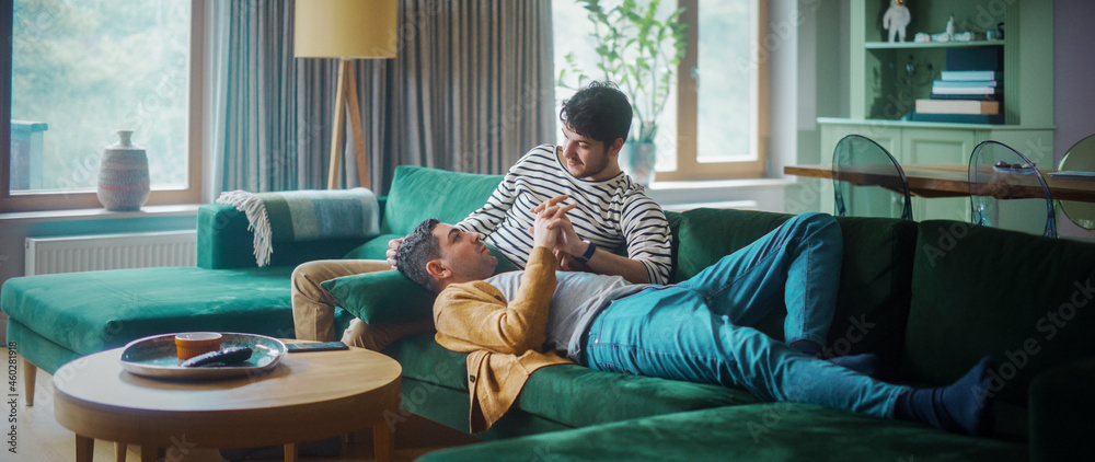 Gentle Scenes of a Stylish Young Adult Gay Couple Spend Time at Home. Two Happy Man in Love Lie Down on Sofa and Cuddle in Casual Clothes. Cute LGBT Relationship Content.