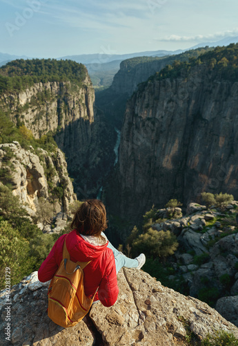 Beautiful view of Tazi Canyon in Turkey, traveler woman sitting on cliff and overlooking canyon with a river on the bottom and rocky walls