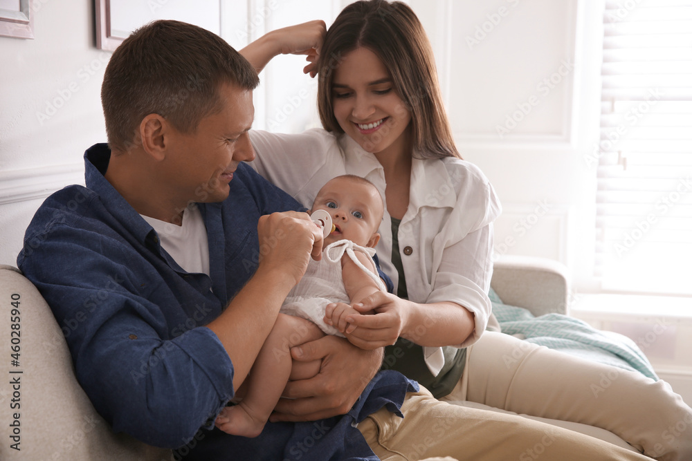 Happy couple holding their cute little baby with pacifier at home Happy couple holding their cute little baby with pacifier at home