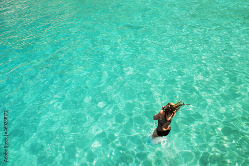 Woman jumping into emerald water in the sea.