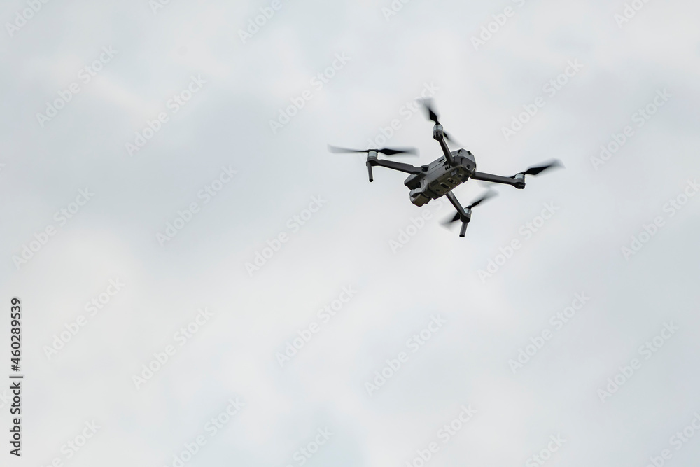 Professional quadcopter flying high in the gray sky Professional quadcopter flying high in the gray sky
