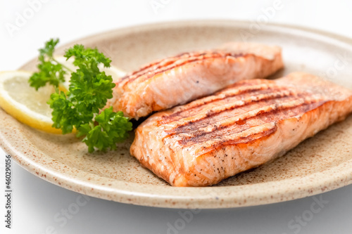 Grilled salmon fillet and lemon slices on a plate. White background. Healthy food. Isolate. Photo