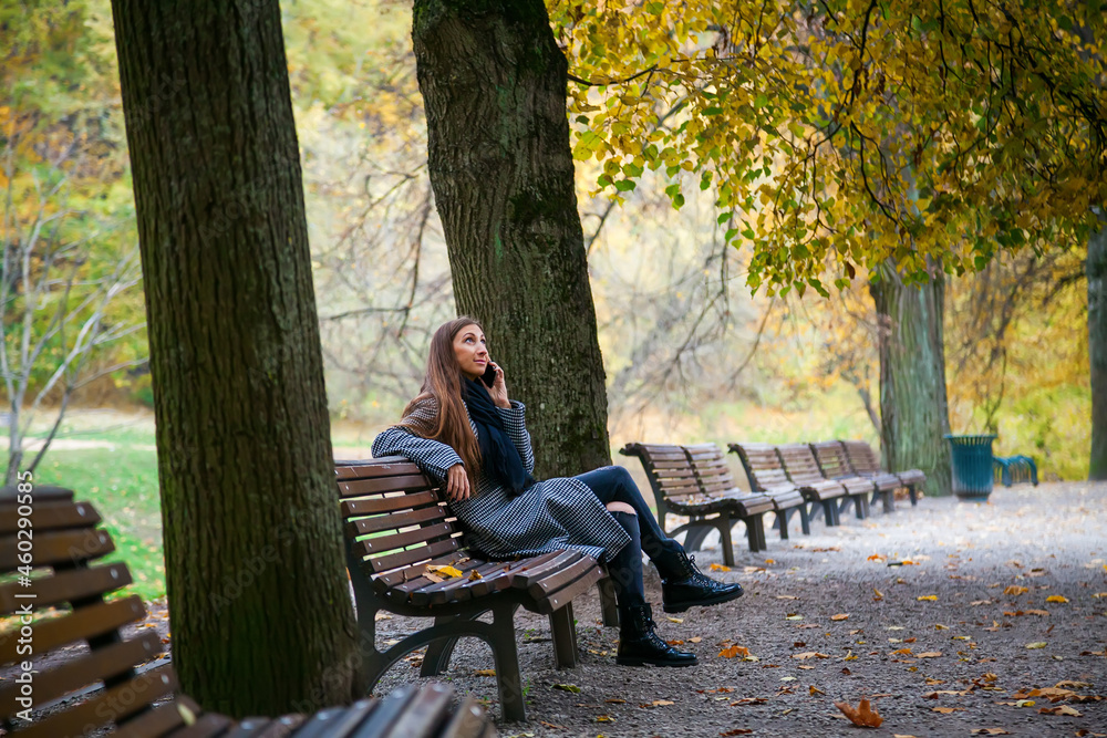 Woman sitting on a bench in autumn city park Woman sitting on a bench in autumn city park