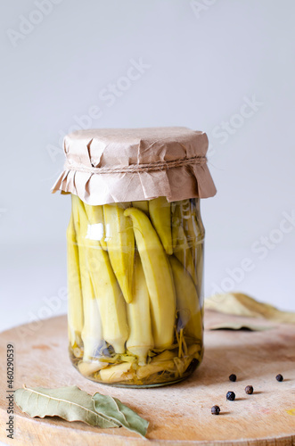 Homemade pickled okra in a glass jar on a gray background. Preservation of vegetables. Close-up