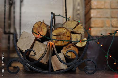 Firewood for the fireplace in a wrought iron basket on a wooden floor