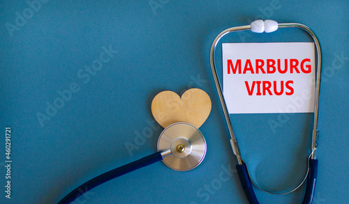 Marburg virus symbol. White card with words Marburg virus, beautiful blue background, wooden heart and stethoscope. Medical, marburg virus concept.