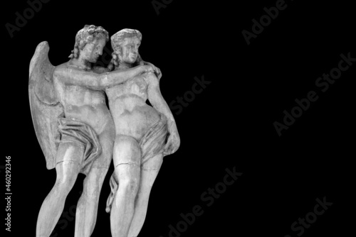 Cupid and Psyche. An ancient stone statue on black background. Copy space.